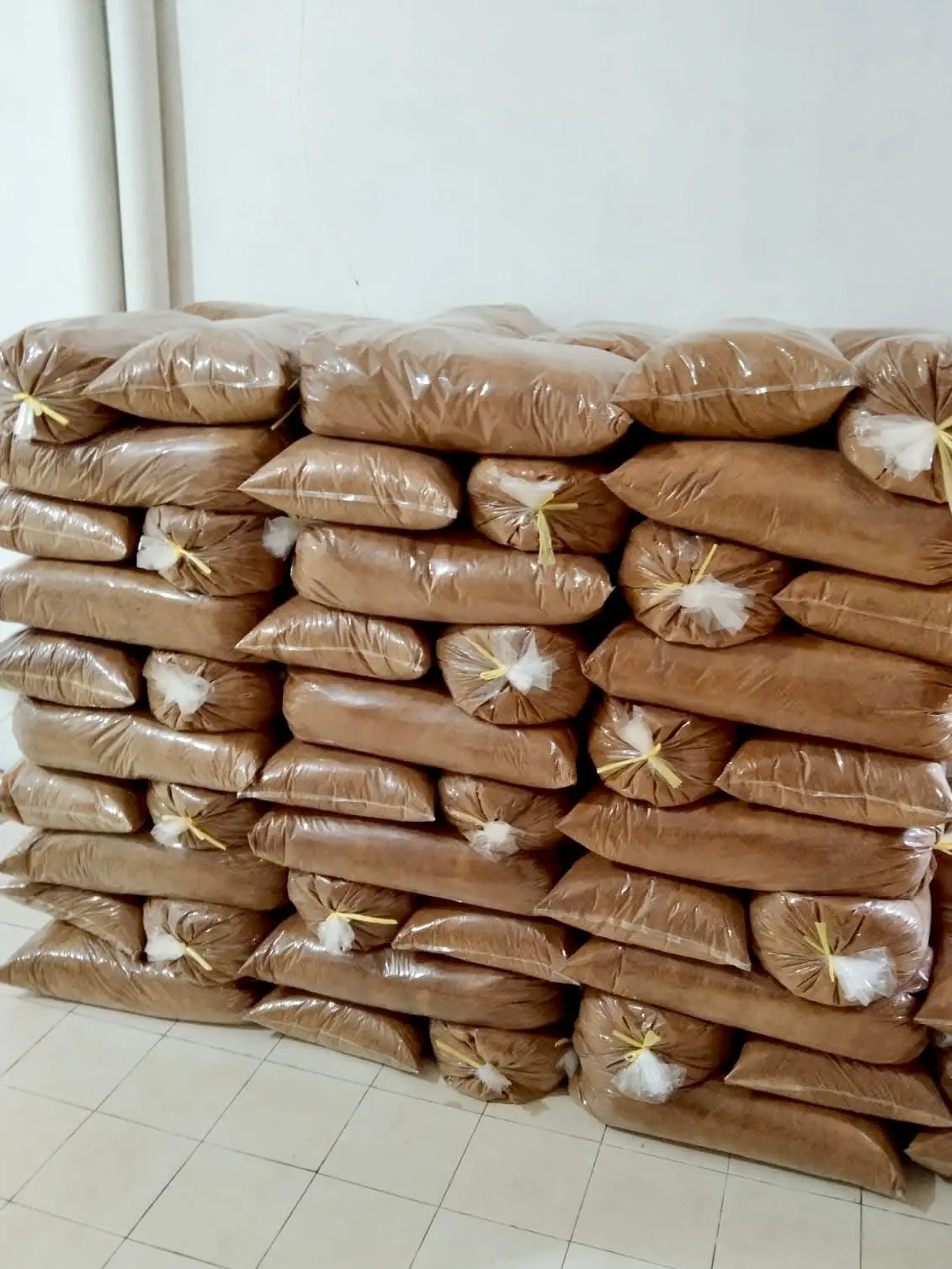 A large stack of packed bags containing brown organic coconut sugar powder, ready for bulk container shipment and logistics. Demonstrates large-scale B2B supply capacity for food manufacturers globally