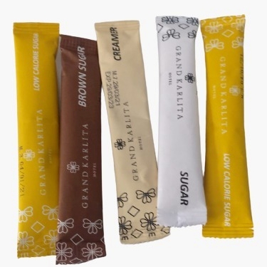 A selection of branded single-serve sugar sticks and creamer sachets, demonstrating custom private label packaging capability for organic coconut sugar and other sweeteners used in the HORECA (Hotel, Restaurant, Cafe) industry
